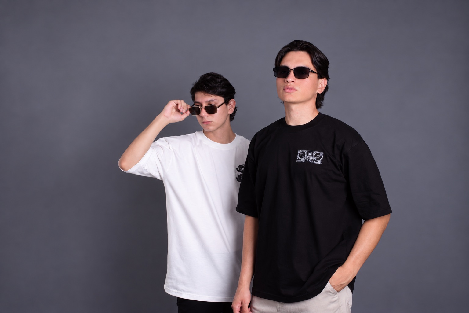 Dos chicos con lentes de sol y poleras oversize blanca y negra de Peppers St.
